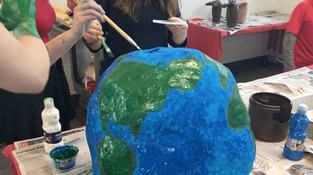 Students painting a paper mache globe