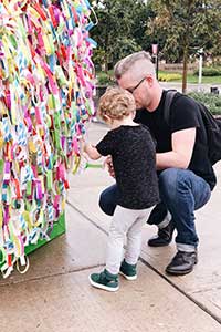Dad and son hanging ribbon on Broken Wings during ArtPrize Ten