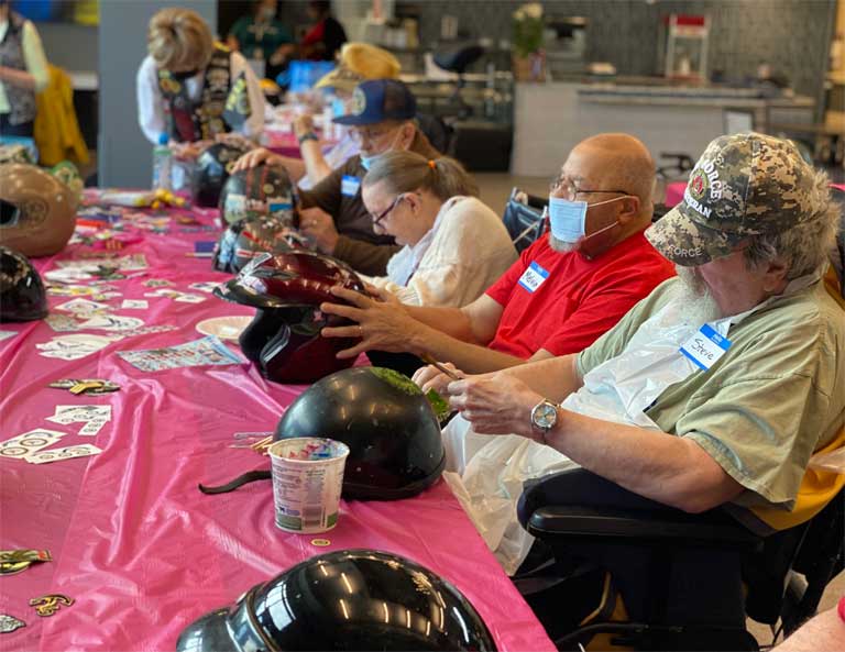 Workshop participants decorate motorcycle helmets for the Stories of Service veteran art project